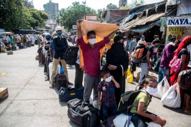 MUMBAI / INDIA - 26 Mayıs 2020: Göçmen işçiler aile üyeleriyle birlikte, önleyici tedbir olarak, ülke çapındaki tecrit sırasında özel bir trene bindikleri için onları tren istasyonuna götürmek üzere sıraya girdiler.