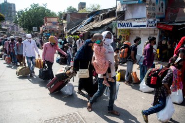 MUMBAI / INDIA - 26 Mayıs 2020: Göçmen işçiler aile üyeleriyle birlikte, önleyici tedbir olarak, ülke çapındaki tecrit sırasında özel bir trene bindikleri için onları tren istasyonuna götürmek üzere sıraya girdiler.