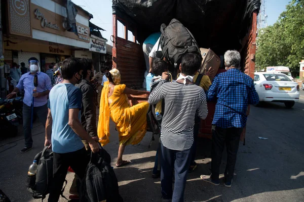MUMBAI / INDIA - 26 Mayıs 2020: Aile üyeleri ile birlikte göçmen işçiler, mahremiyete karşı önleyici bir tedbir olarak ülke çapındaki tecrit sırasında memleketlerine dönüş yolculuklarında özel bir trene bindikleri için tren terminaline gitmek üzere kamyonla seyahat ediyorlar.