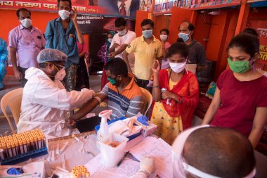 MUMBAI / INDIA - 30 Mayıs 2020: Bir tıp çalışanı COVID-19 Coronavirus için ulusal sero araştırması sırasında Dharavi 'deki insanların kan örneklerini topluyor