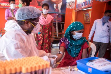 MUMBAI / INDIA - 30 Mayıs 2020: Bir tıp çalışanı COVID-19 Coronavirus için ulusal sero araştırması sırasında Dharavi 'de bir kadının kan örneğini topluyor