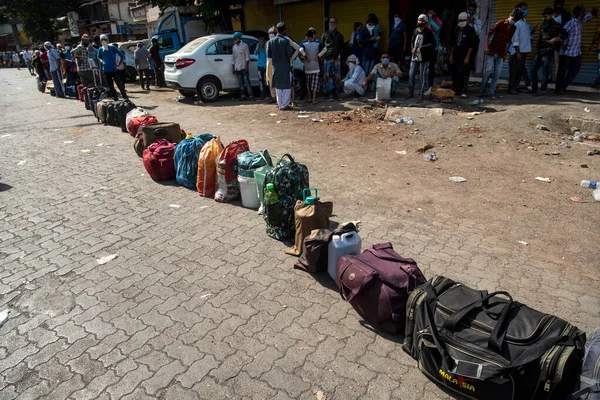 MUMBAI / INDIA - 26 Mayıs 2020: Göçmen işçiler, ülke çapındaki tecrit sırasında ülkeye dönüş yolculuklarına özel bir trene bindikleri için kendilerini tren terminaline götürecek otobüse binmek üzere bagajlarını kuyruğa bırakıyorlar. 