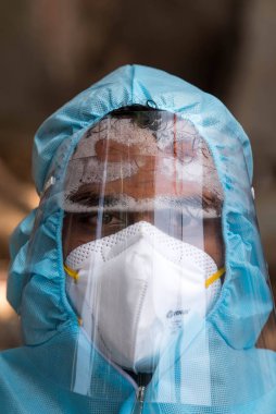 MUMBAI / INDIA - 10 Haziran 2020: Bir sağlık çalışanı COVID-19 Coronavirus test sürücüsü Dharavi 'de COVID-19 Coronavirus salgını sırasında örnek toplarken PPE kitinin içinde terler