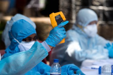 MUMBAI / INDIA - 10 Haziran 2020: COVID test sürüşünde koruyucu ekipman giyen bir tıbbi personel, COVID-19 Coronavirus salgını sırasında Dharavi 'de vücut ısısını gözlemler