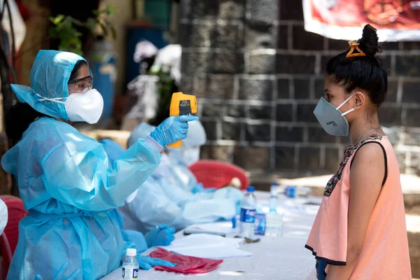 MUMBAI / INDIA - 10 Haziran 2020: COVID test sürüşünde koruyucu ekipman giyen bir tıbbi personel, COVID-19 Coronavirus salgını sırasında Dharavi 'de vücut ısısını gözlemler