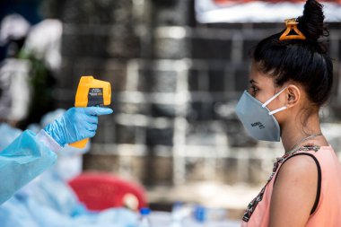 MUMBAI / INDIA - 10 Haziran 2020: COVID test sürüşünde koruyucu ekipman giyen bir tıbbi personel, COVID-19 Coronavirus salgını sırasında Dharavi 'de vücut ısısını gözlemler