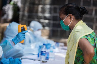 MUMBAI / INDIA - 10 Haziran 2020: COVID test sürüşünde koruyucu ekipman giyen bir tıbbi personel, COVID-19 Coronavirus salgını sırasında Dharavi 'de vücut ısısını gözlemler