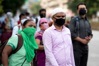 MUMBAI/INDIA- JUNE 10, 2020: Commuters wearing a facemask wait to board a public transport bus in Mumbai. India has begun gradually lifting its restrictions imposed by the government.