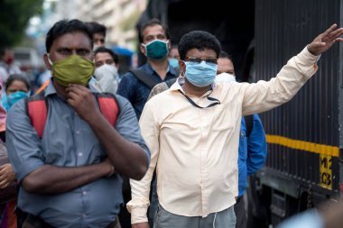 MUMBAI/INDIA- JUNE 10, 2020: Commuters wearing a facemask wait to board a public transport bus in Mumbai. India has begun gradually lifting its restrictions imposed by the government.