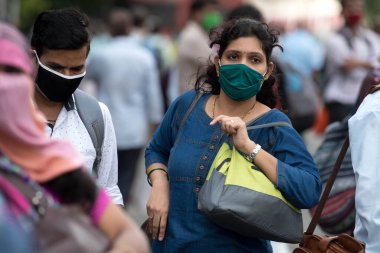 MUMBAI/INDIA- JUNE 10, 2020: Commuters wearing a facemask wait to board a public transport bus in Mumbai. India has begun gradually lifting its restrictions imposed by the government.