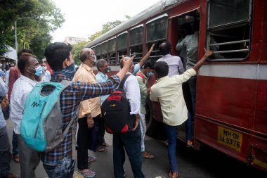 MUMBAI/INDIA- JUNE 10, 2020: Commuters wearing a facemask board a public transport bus in Mumbai. India has begun gradually lifting its restrictions imposed by the government.