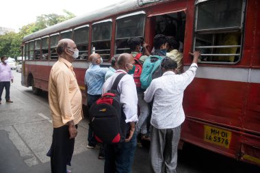 MUMBAI/INDIA- JUNE 10, 2020: Commuters wearing a facemask wait to board a public transport bus in Mumbai. India has begun gradually lifting its restrictions imposed by the government.