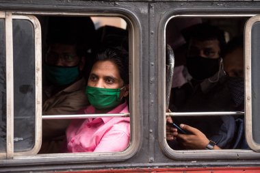 MUMBAI/INDIA- JUNE 10, 2020: Commuters wearing a facemask travel by public transport bus in Mumbai. India has begun gradually lifting its restrictions imposed by the government.