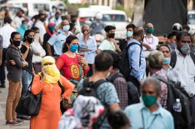 MUMBAI/INDIA- JUNE 10, 2020: Commuters wearing a facemask wait to board a public transport bus in Mumbai. India has begun gradually lifting its restrictions imposed by the government.