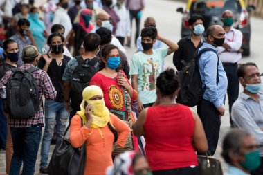 MUMBAI/INDIA- JUNE 10, 2020: Commuters wearing a facemask wait to board a public transport bus in Mumbai. India has begun gradually lifting its restrictions imposed by the government.