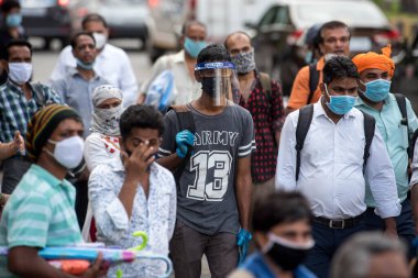 MUMBAI/INDIA- JUNE 10, 2020: Commuters wearing a facemask wait to board a public transport bus in Mumbai. India has begun gradually lifting its restrictions imposed by the government.