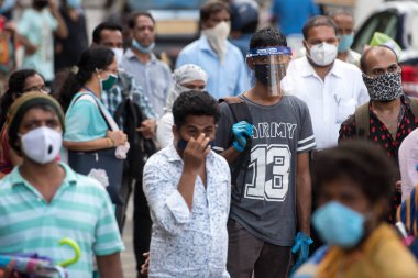 MUMBAI/INDIA- JUNE 10, 2020: Commuters wearing a facemask wait to board a public transport bus in Mumbai. India has begun gradually lifting its restrictions imposed by the government.