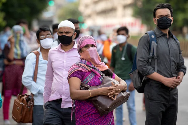 MUMBAI/INDIA- JUNE 10, 2020: Commuters wearing a facemask wait to board a public transport bus in Mumbai. India has begun gradually lifting its restrictions imposed by the government.