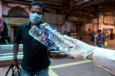 MUMBAI/INDIA - JUNE 14, 2020: Volunteers distribute food and water bottle to passenger at Chhatrapati Shivaji Maharaj Terminus for boarding a special train back home during a nationwide lockdown.
