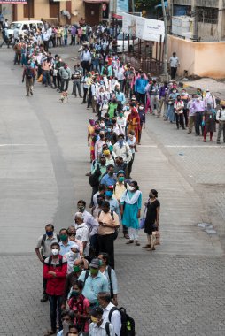 MUMBAI/INDIA- JUNE 15, 2020: Commuters wearing a facemask stand in queue wait to board a public transport bus in Dombivali. India has begun gradually lifting its restrictions imposed by the government.