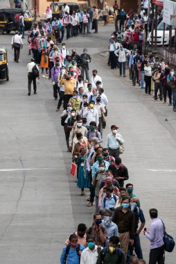 MUMBAI/INDIA- JUNE 15, 2020: Commuters wearing a facemask stand in queue wait to board a public transport bus in Dombivali. India has begun gradually lifting its restrictions imposed by the government.
