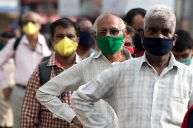 MUMBAI/INDIA- JUNE 15, 2020: Commuters wearing a facemask stand in queue wait to board a public transport bus in Dombivali. India has begun gradually lifting its restrictions imposed by the government.