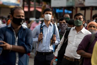 MUMBAI/INDIA- JUNE 15, 2020: Commuters wearing a facemask stand in queue wait to board a public transport bus in Dombivali. India has begun gradually lifting its restrictions imposed by the government.