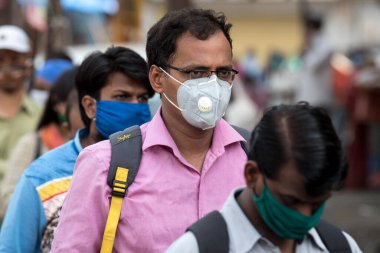 MUMBAI/INDIA- JUNE 15, 2020: Commuters wearing a facemask stand in queue wait to board a public transport bus in Dombivali. India has begun gradually lifting its restrictions imposed by the government.