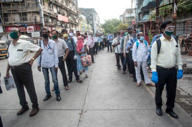 MUMBAI/INDIA- JUNE 15, 2020: Commuters wearing a facemask stand in queue wait to board a public transport bus in Dombivali. India has begun gradually lifting its restrictions imposed by the government.