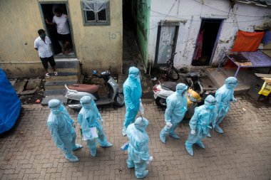 MUMBAI/INDIA- JUNE 17, 2020: Health workers wearing protective kit arrive at the COVID health check up camp at Ramabai colony slum during the COVID-19 Coronavirus pandemic.