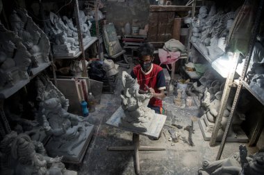 MUMBAI / INDIA - 20 Haziran 2020: Yüz maskesi takan bir sanatçı COVID-19 Coronavirus salgını sırasında Girgaon 'daki atölyesinde fil başlı Hindu tanrı Ganesha' yı putlaştırdı.