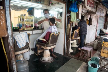 MUMBAI / INDIA - 28 Haziran 2020: Maskeli berberler, Santacruz 'daki bir müşteriye kişisel bakım hizmetlerinin tecrit uygulamasının gevşetilmesinin ardından devam etmesine izin verildikten sonra baktılar.
