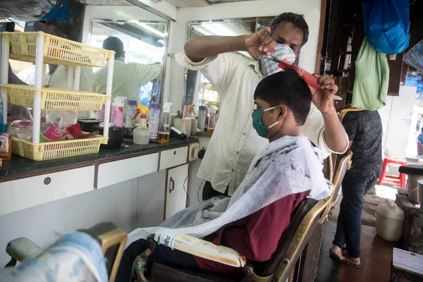 MUMBAI / INDIA - 28 Haziran 2020: Maskeli berberler, Santacruz 'daki bir müşteriye kişisel bakım hizmetlerinin tecrit uygulamasının gevşetilmesinin ardından devam etmesine izin verildikten sonra baktılar.