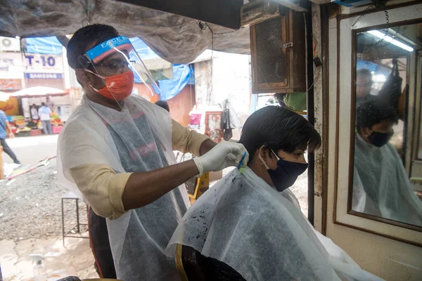 MUMBAI / INDIA - 28 Haziran 2020: Maskeli berberler, Santacruz 'daki bir müşteriye kişisel bakım hizmetlerinin tecrit uygulamasının gevşetilmesinin ardından devam etmesine izin verildikten sonra baktılar.