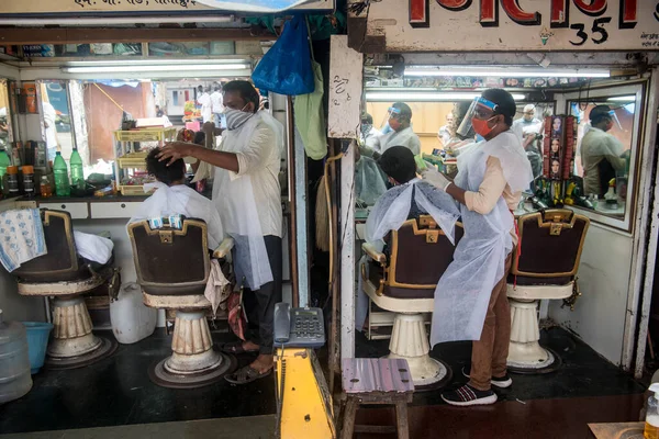 MUMBAI / INDIA - 28 Haziran 2020: Maskeli berberler, Santacruz 'daki bir müşteriye kişisel bakım hizmetlerinin tecrit uygulamasının gevşetilmesinin ardından devam etmesine izin verildikten sonra baktılar.
