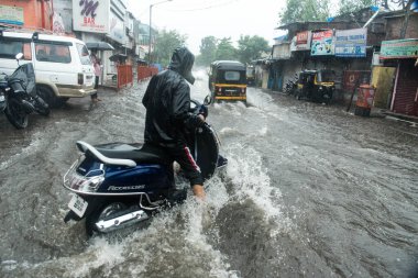 MUMBAI / INDIA - 5 Temmuz 2020: Bombay 'da sağanak yağış sırasında, banliyö sakinleri sel basmış bir sokaktan arabayla geçiyorlar.