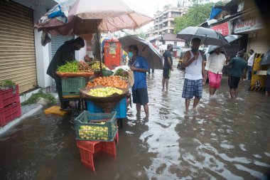 MUMBAI / INDIA - 5 Temmuz 2020: Müşteriler Kurla 'da sağanak yağış sonrasında sel basmış bir caddedeki bir sokak dükkanından sebze satın alır.