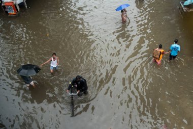 MUMBAI / INDIA - 5 Temmuz 2020: Şiddetli yağmurlar sırasında insanlar Chembur 'da sel basmış bir caddede yürür.