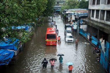 MUMBAI / INDIA - 5 Temmuz 2020: Şiddetli yağmurlar sırasında insanlar Chembur 'da sel basmış bir caddede yürür.
