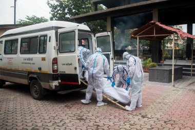 MUMBAI / INDIA - 7 Temmuz 2020: Kişisel koruyucu ekipman giyen cenaze işçileri, COVID-19 'dan ölen bir kişinin cesedini Mumbai yakınlarındaki Panvel' deki bir krematoryuma taşıdılar..