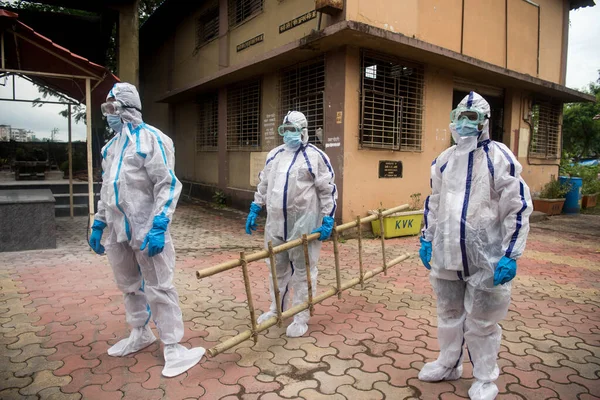 MUMBAI / INDIA - 7 Temmuz 2020: Mumbai yakınlarındaki Panvel 'de yakılan COVID-19 kurbanının yakılması için kişisel koruma ekipmanı takan cenaze işçileri.