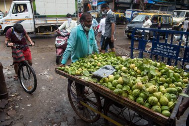 MUMBAI / INDIA - 3 AĞUSTOS 2020: Bir satıcı COVID-19 Coronavirus salgını sırasında Guava ile birlikte Dharavi varoşlarında meyve arabasını itiyor.