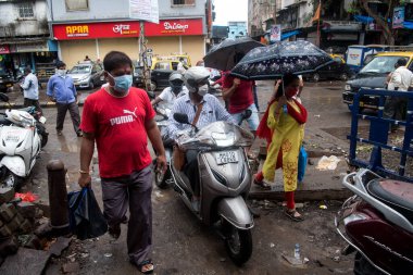 MUMBAI / INDIA - 3 AĞUSTOS 2020: Motosikletçiler sabah trafiği sırasında Dharavi varoşlarında seyahat ederken maske takarlar.