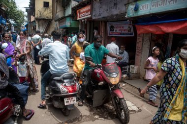 MUMBAI / INDIA - 3 AĞUSTOS 2020: Motosikletçiler COVID-19 Coronavirus salgını sırasında Dharavi varoşlarında seyahat ederken maske takarlar.