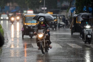 MUMBAI / INDIA - 5 AĞUSTOS 2020: Sakinaka 'da sağanak yağış sırasında motosiklet süren bir adam.