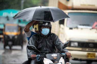 MUMBAI / INDIA - 5 AĞUSTOS 2020: Sakinaka 'da sağanak yağış sırasında motosiklet süren bir adam.
