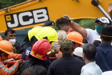 MAHARASHTRA / INDIA - 25 Ağustos 2020: Kurtarma ekipleri, Mahad 'da beş katlı çökmüş bir apartmanın enkazından çıkarılan dört yaşındaki bir çocuğu taşıdılar.