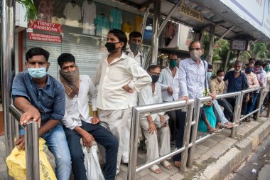 MUMBAI / INDIA - 12 Ekim 2020: Bir Covid-19 koronavirüs salgını sırasında Andheri 'de toplu taşıma otobüsüne binmek için maske takan banliyö sakinleri bekleyin. 