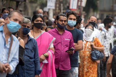 MUMBAI / INDIA - 12 Ekim 2020: Bir Covid-19 koronavirüs salgını sırasında Andheri 'de toplu taşıma otobüsüne binmek için maske takan banliyö sakinleri bekleyin. 