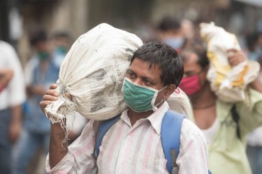 MUMBAI / INDIA - 12 Ekim 2020: Bir Covid-19 koronavirüs salgını sırasında Andheri 'de toplu taşıma otobüsüne binmek için maske takan banliyö sakinleri bekleyin. 